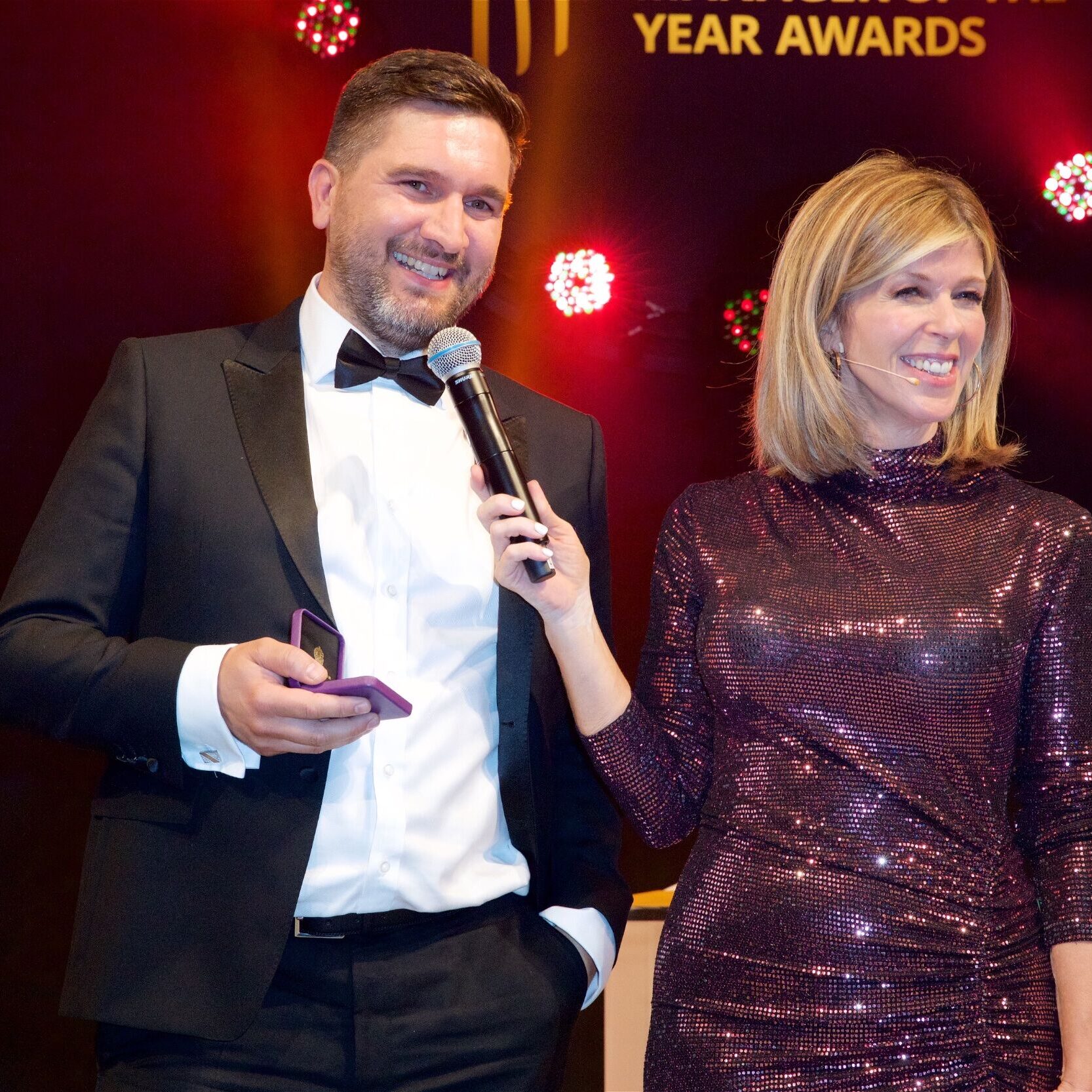 Awards ceremony presenters smiling on stage