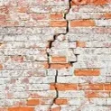 Whitewashed brick wall with vertical crack